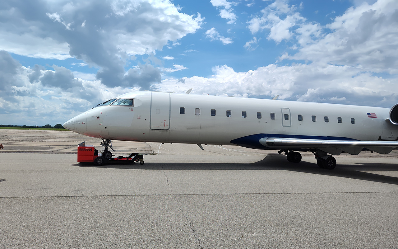A white jet plane on a tarmac on a sunny day.