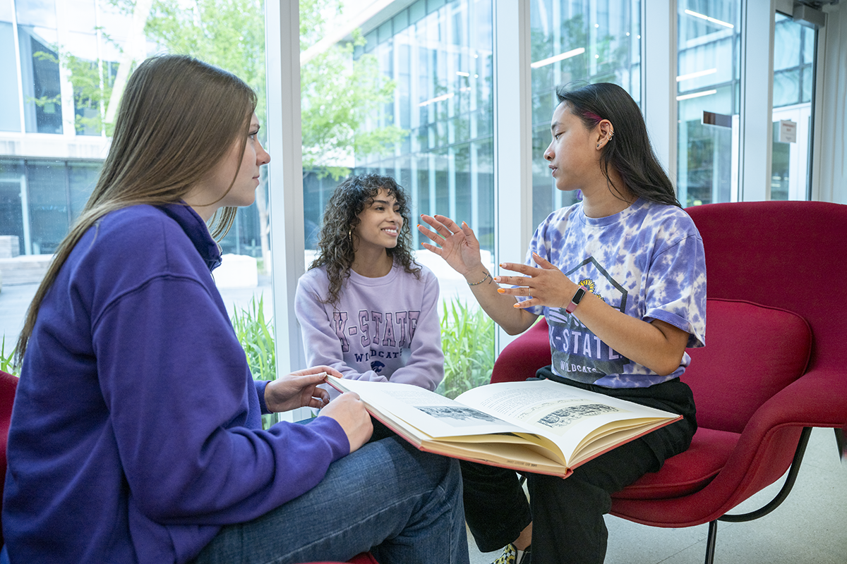 A trio of college students have a conversation in a lobby.