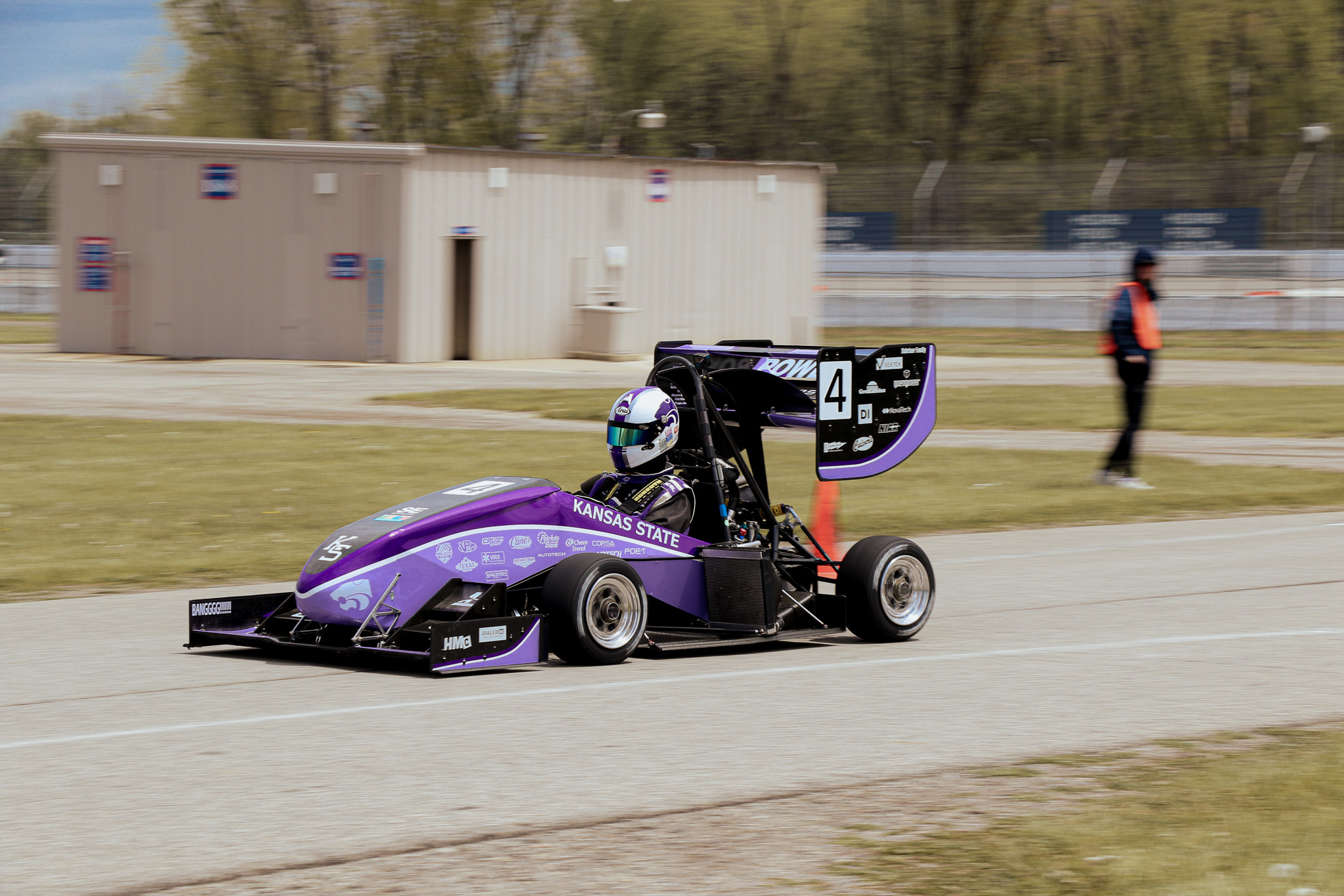 A purple Formula SAE car decked out in purple races down the track.
