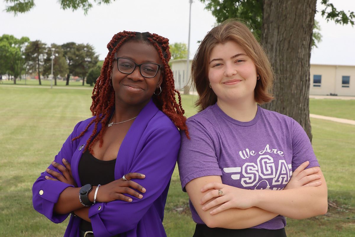 Two female college students at Kansas State University Salina smile for a portrait outside.