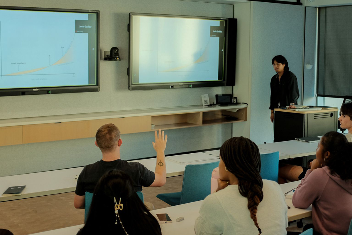 An architecture graduate student gives a presentation on sketching at the head of a college classroom.