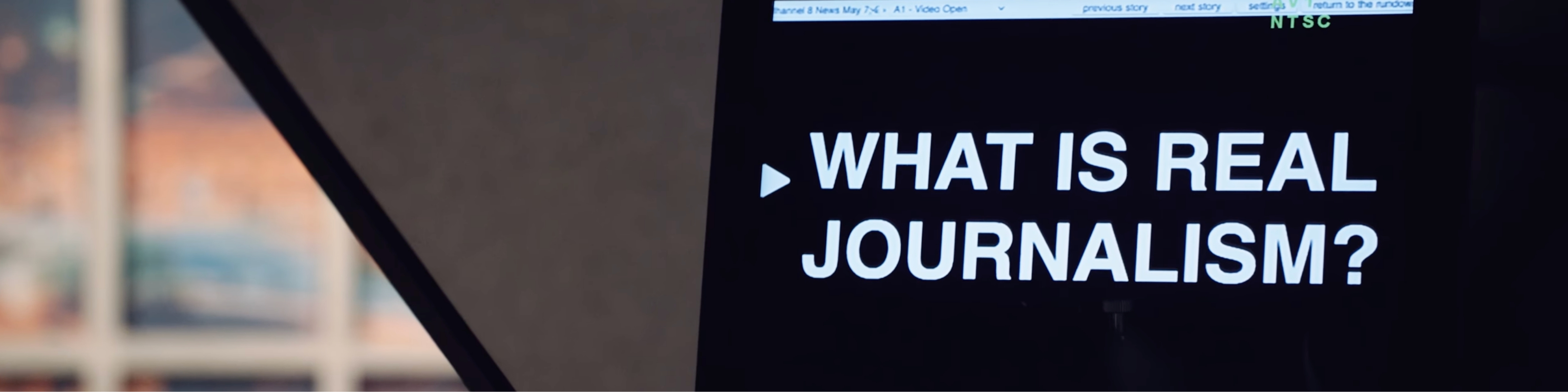 A close up image of a TV screen reader stating "What is real journalism?" in white lettering on black text.