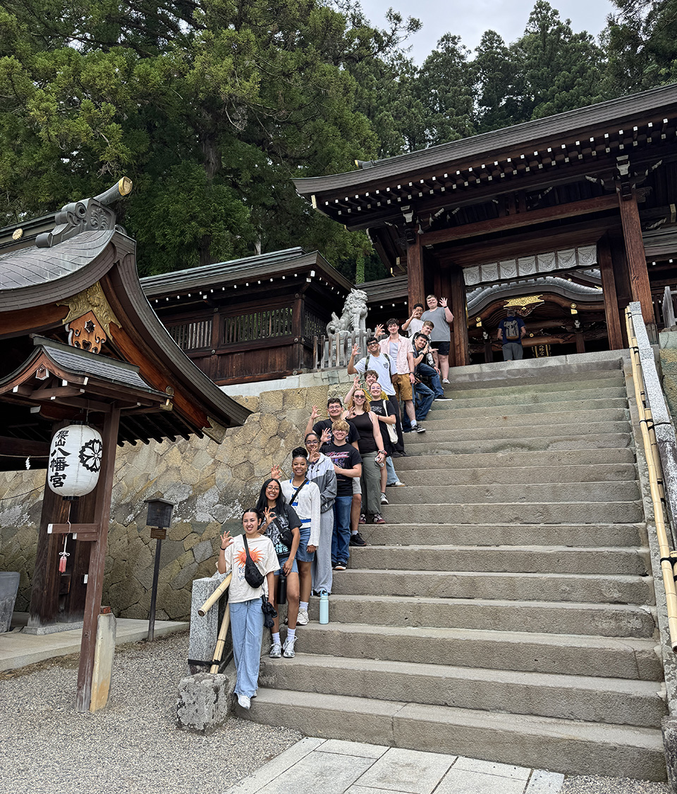 A group stands along a stairway in front of a shrine.