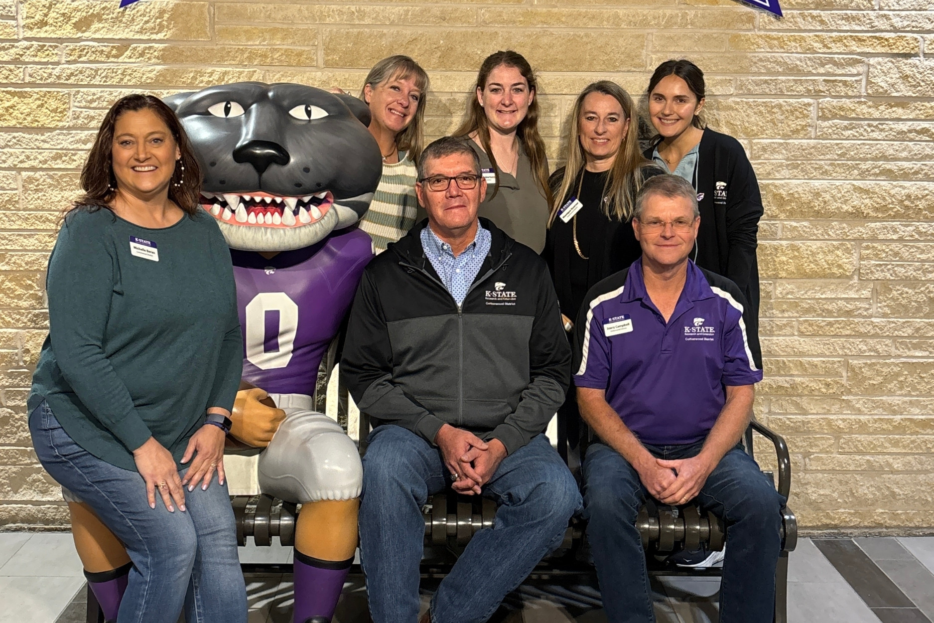 A group of people pose with a Willie the Wildcat statue. 
