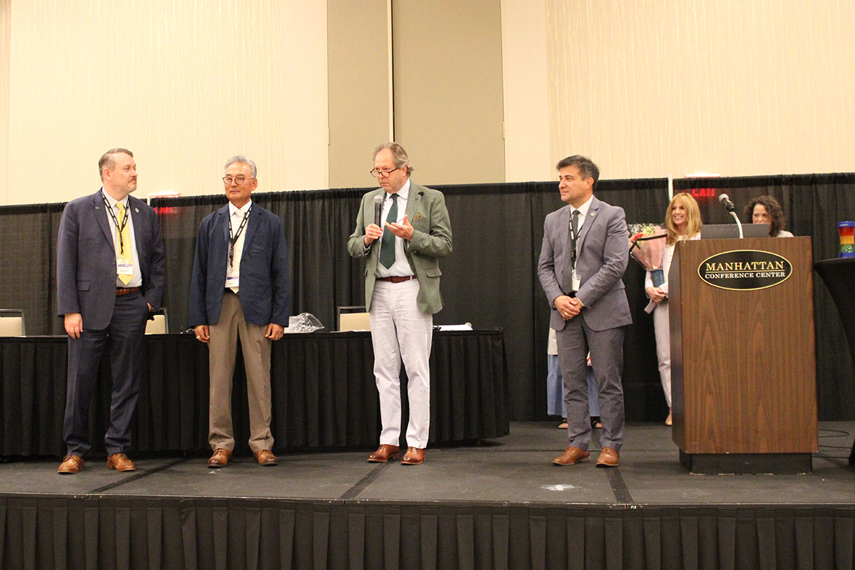 Four college-level faculty and researchers stand together in an open forum hall.