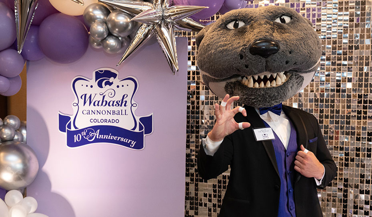 Willie the Wildcat wears a tuxedo and does the K-State hand sign. 