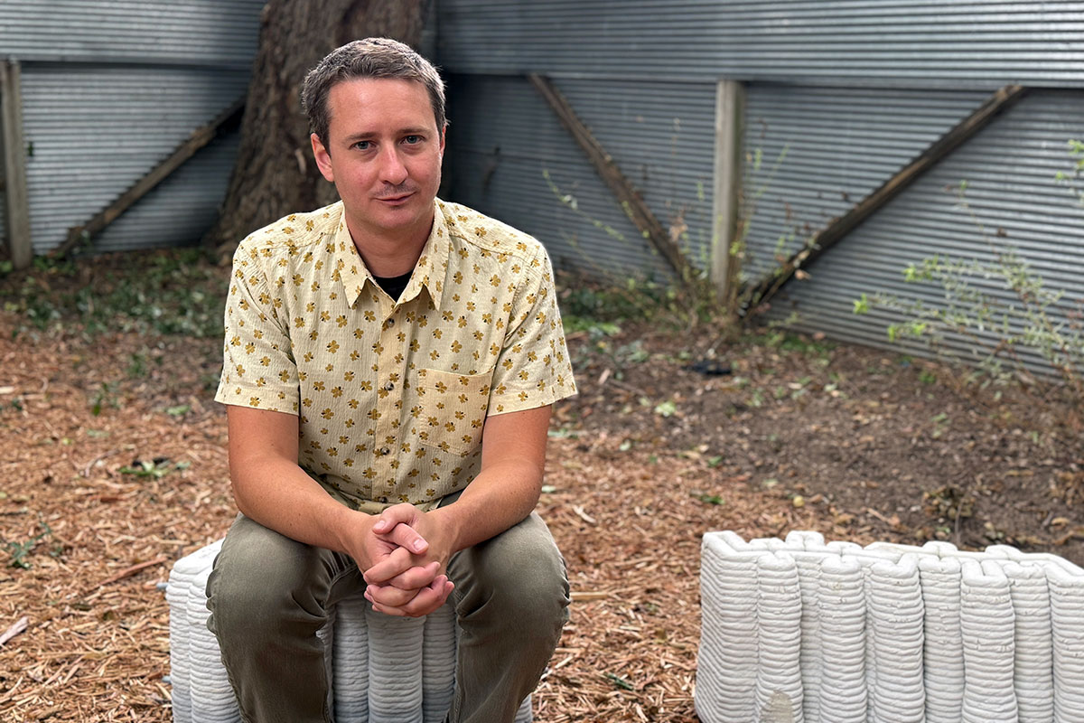 Reese Greenlee sits on a 3D-printed concrete building block