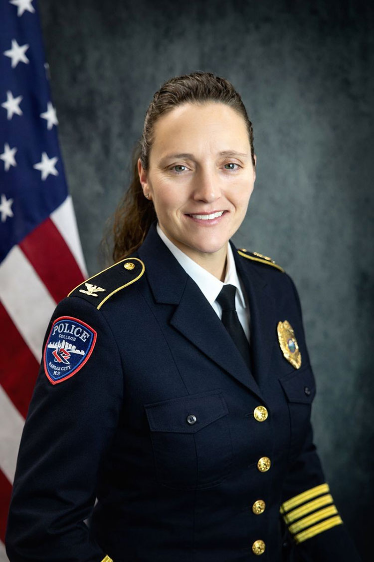 Portrait of a woman with dark hair in a police uniform with an American flag in the background