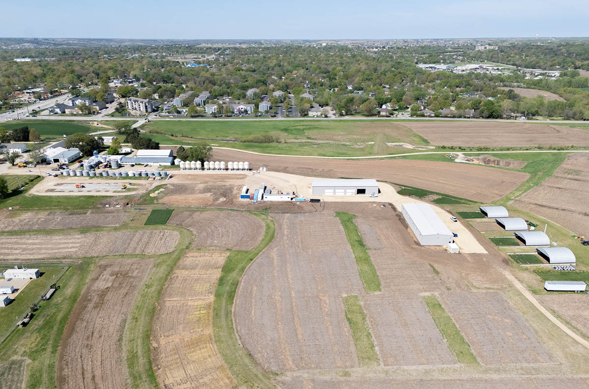 A view of an agronomy complex featuring two buildings and four rounded shelters surrounded by fields.
