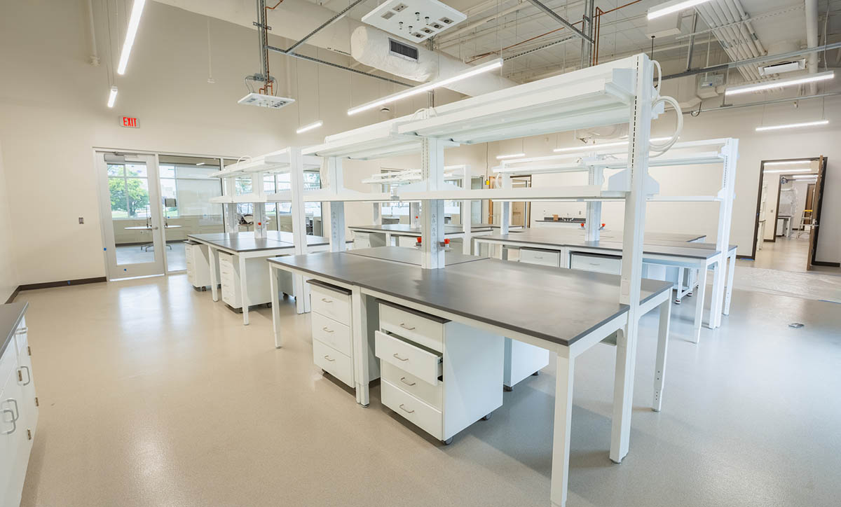 An agronomy lab is shown with black tables, white light fixtures and white drawers.