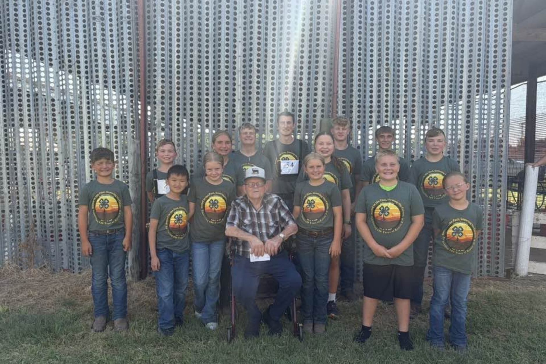 Marion Alpers, surrounded by 14 of his great-grandchildren wearing matching 4-H t-shirts.