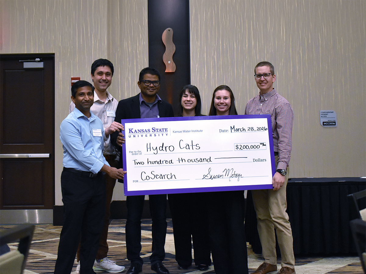 A group of university faculty pose for a portrait while holding a large check, handwritten for $200,000.