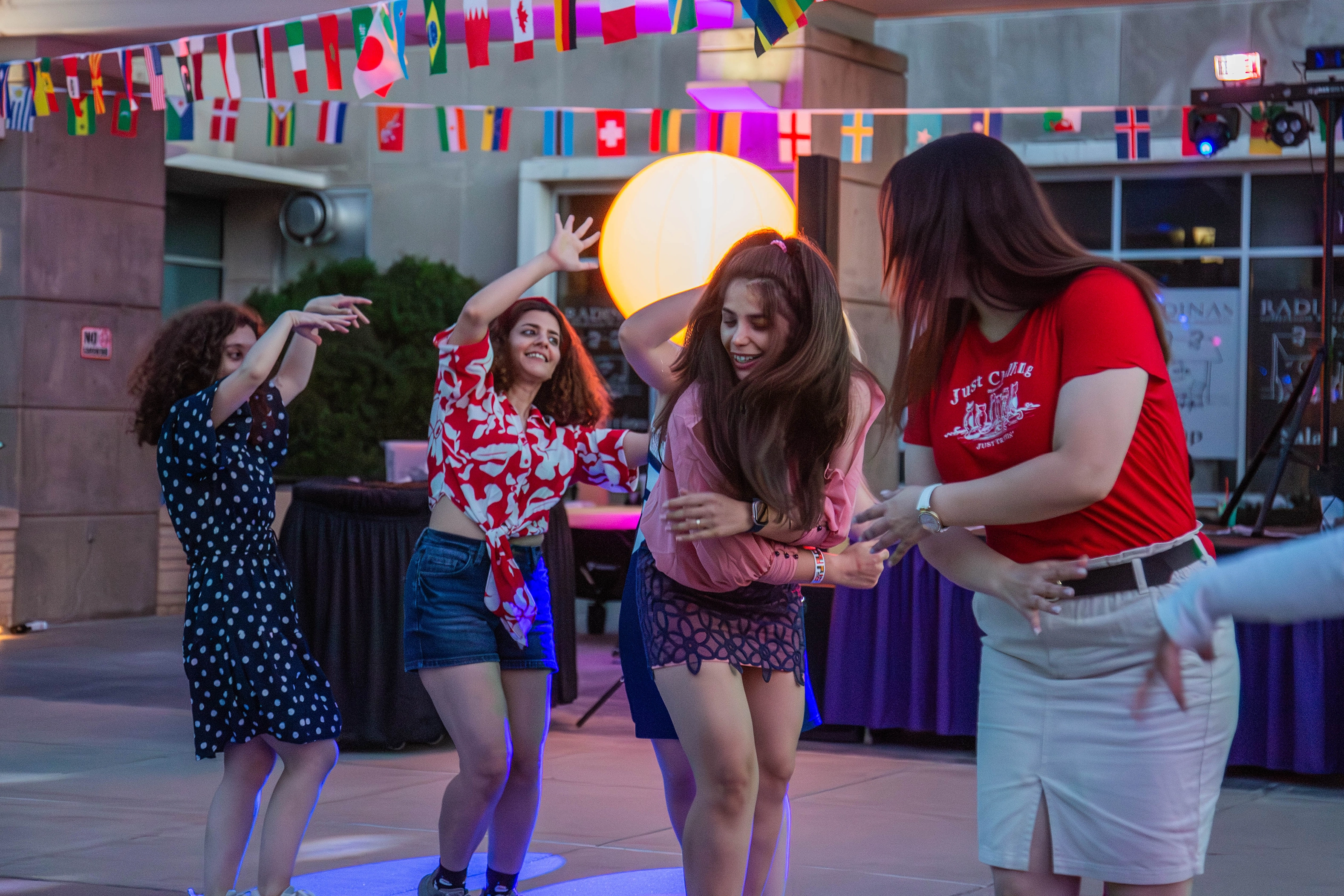 A group of students dancing in a circle with bright lights around them.  