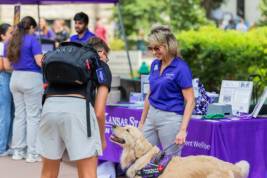 A student petting Oakley, the university service dog.  