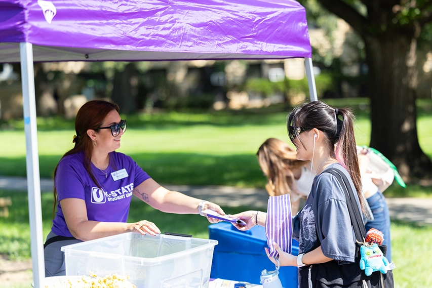 A student grabbing a bag of popcorn from a staff member.