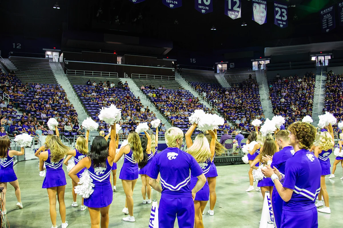 A crowd sitting in seats with cheer team performing on the floor.