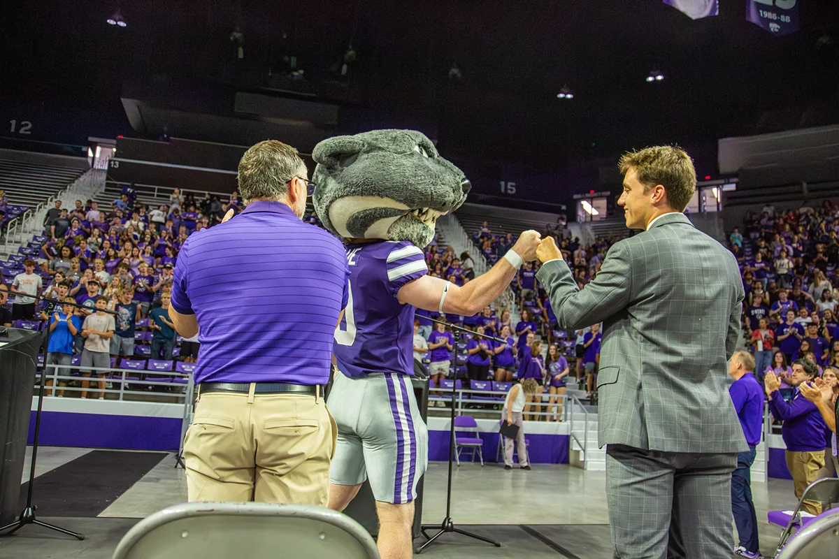 Caden standing up and fisting bumping K-State's mascot, Willie.