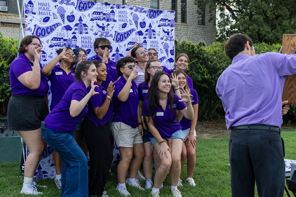 A group of students & staff members pose for a photo in the photo booth. 