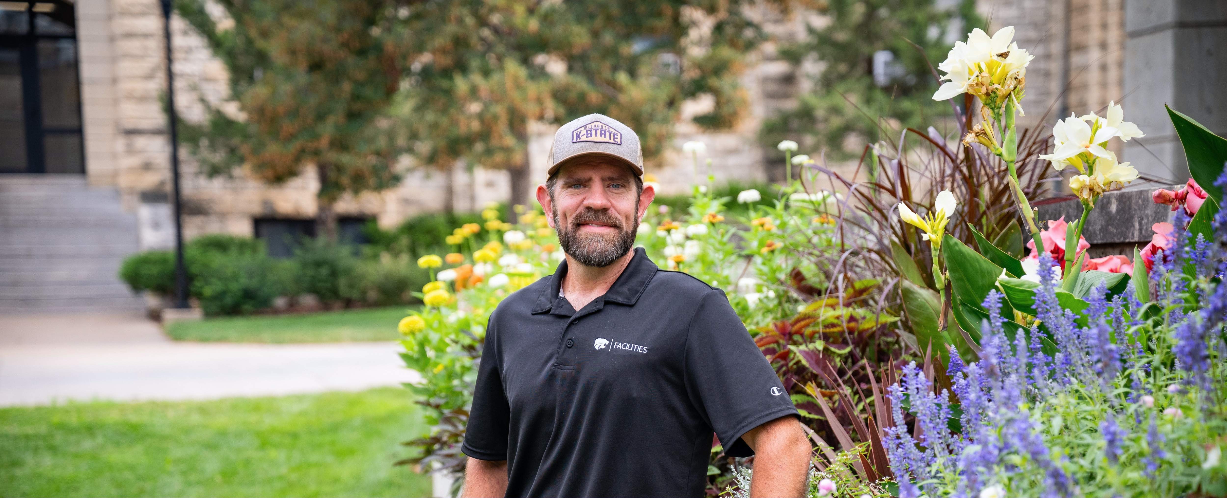 Steven Snyder poses next to a landscaping display outside of K-State's Bosco Plaza
