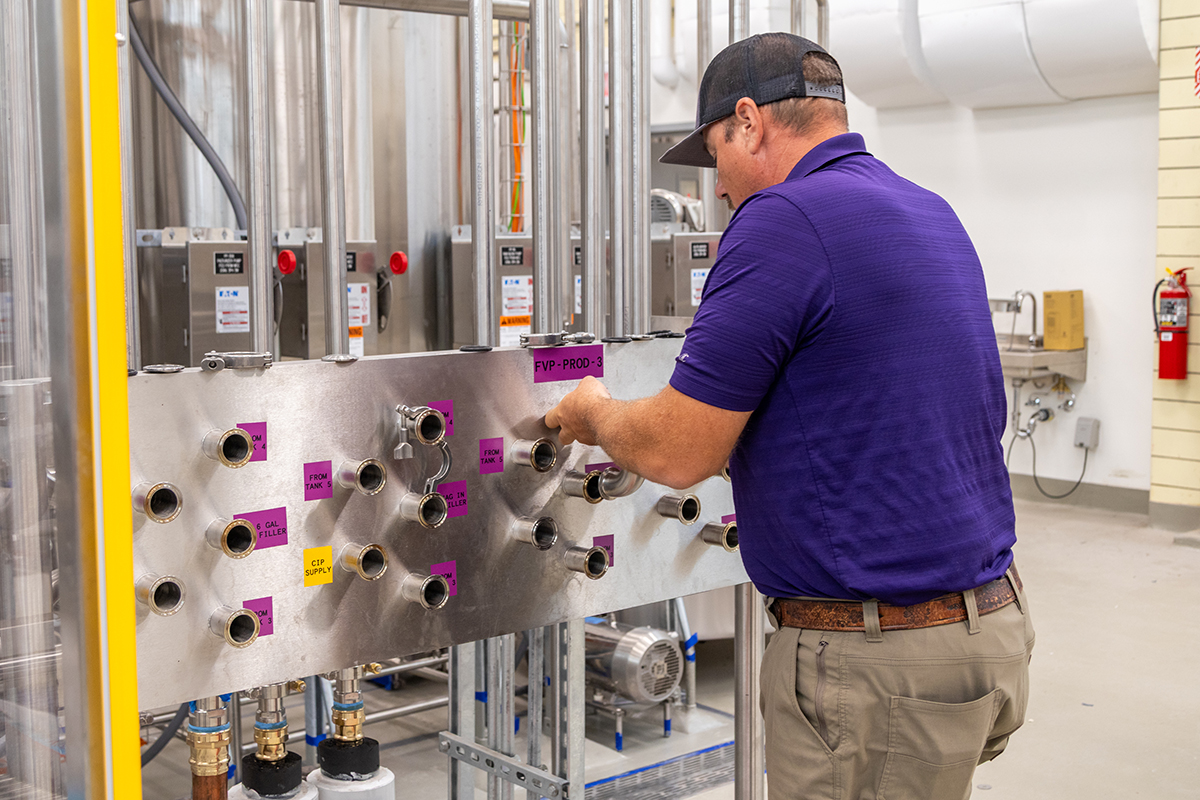 A man demonstrates a new panel of pipe connections in a dairy plant.