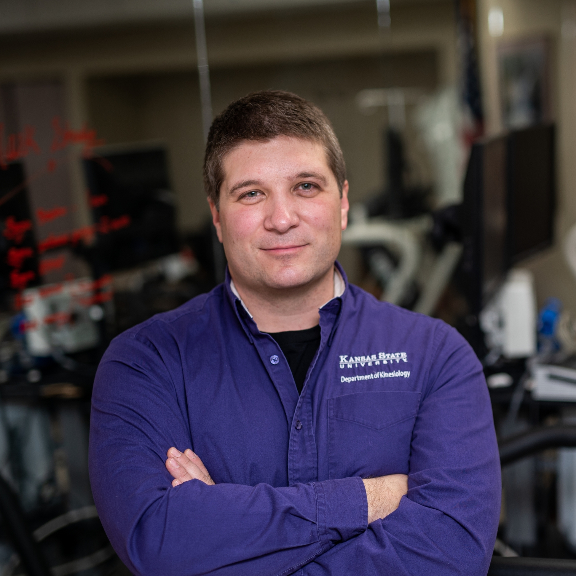 Carl Ade poses in his lab, wearing a purple long-sleeve button-up shirt.
