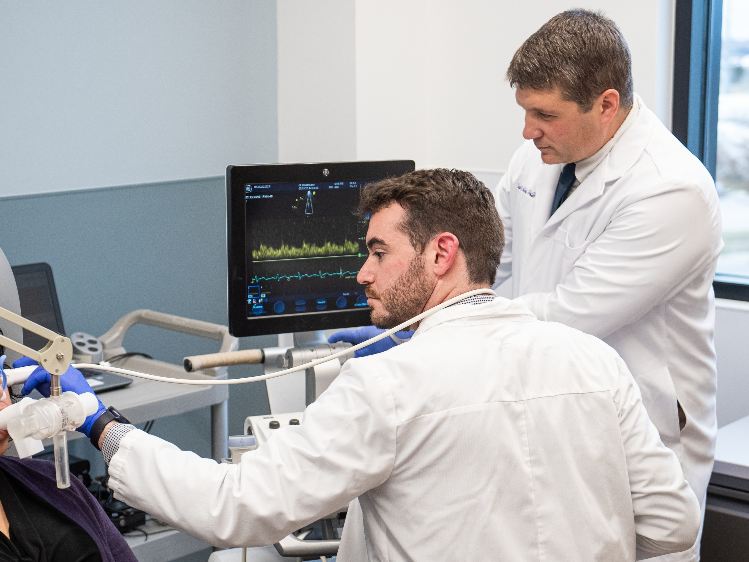 Britton Scheuermann works with a patient in the lab, while Carl Ade oversees.