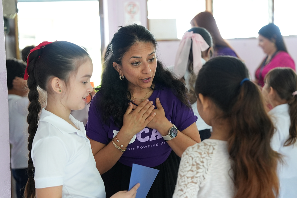 A college professor holds a discussion using gestures with young Costa Rican elementary school students.