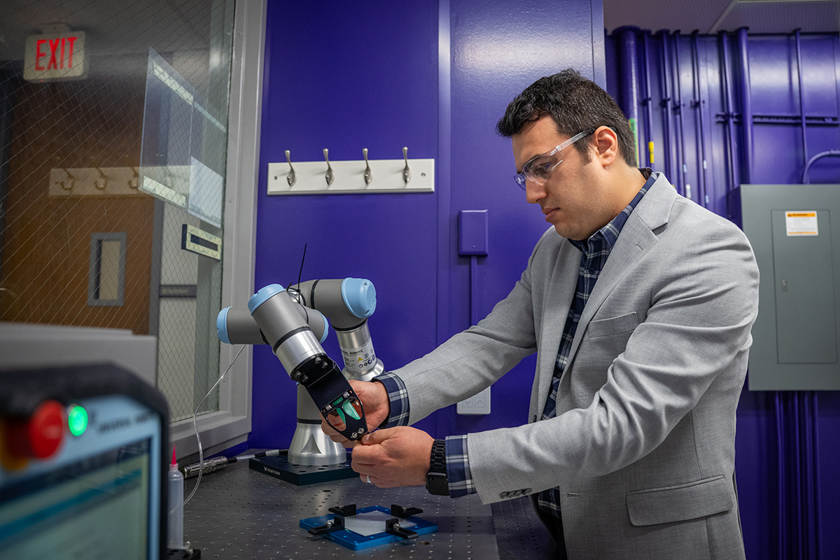 A man in a gray suit adjusts a robotic arm