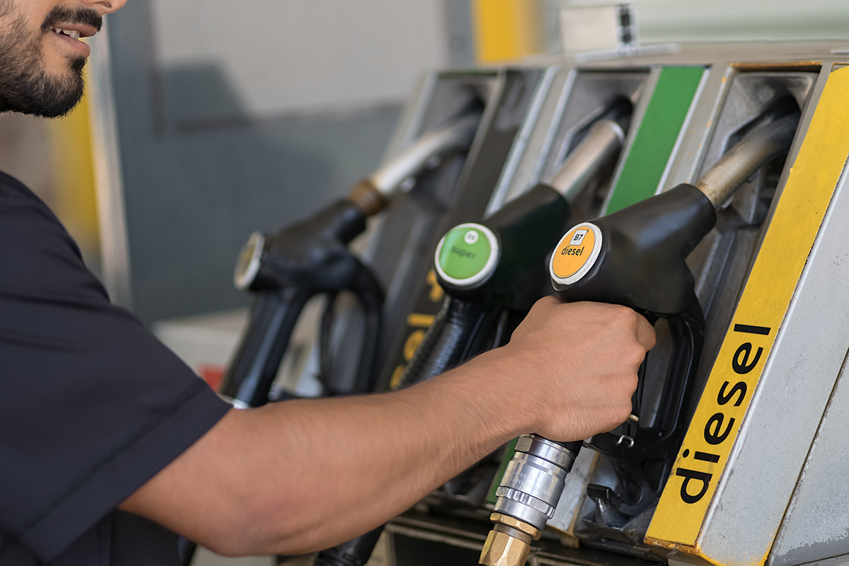 A man grabs a yellow fuel nozzle labeled 