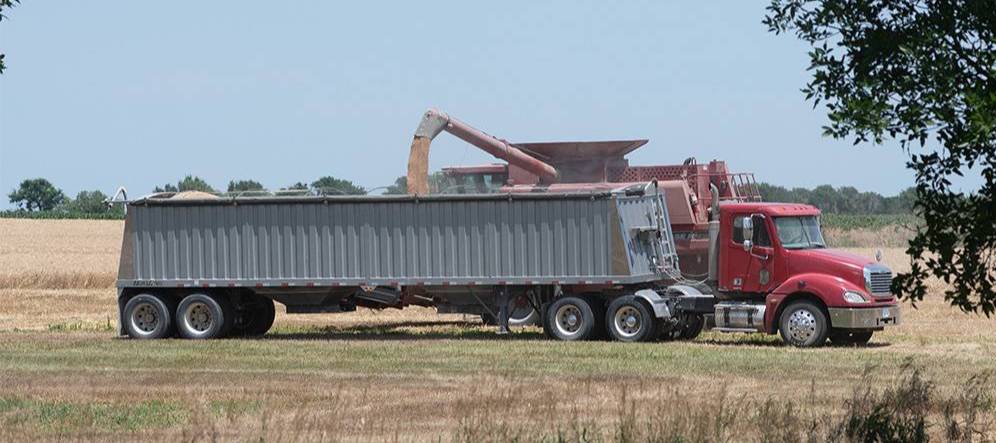A diesel truck and piece of farm equipment are shown in field.