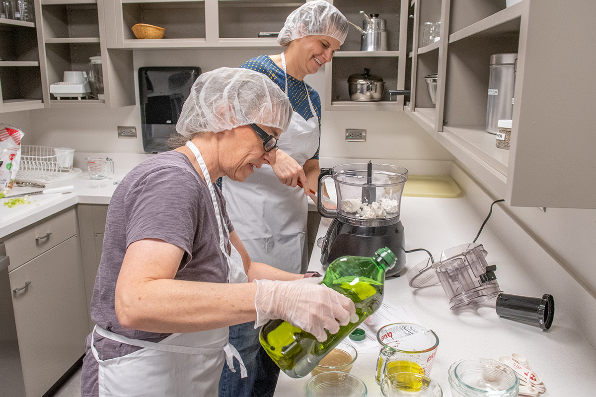 A couple of women work in a kitchen classroom.
