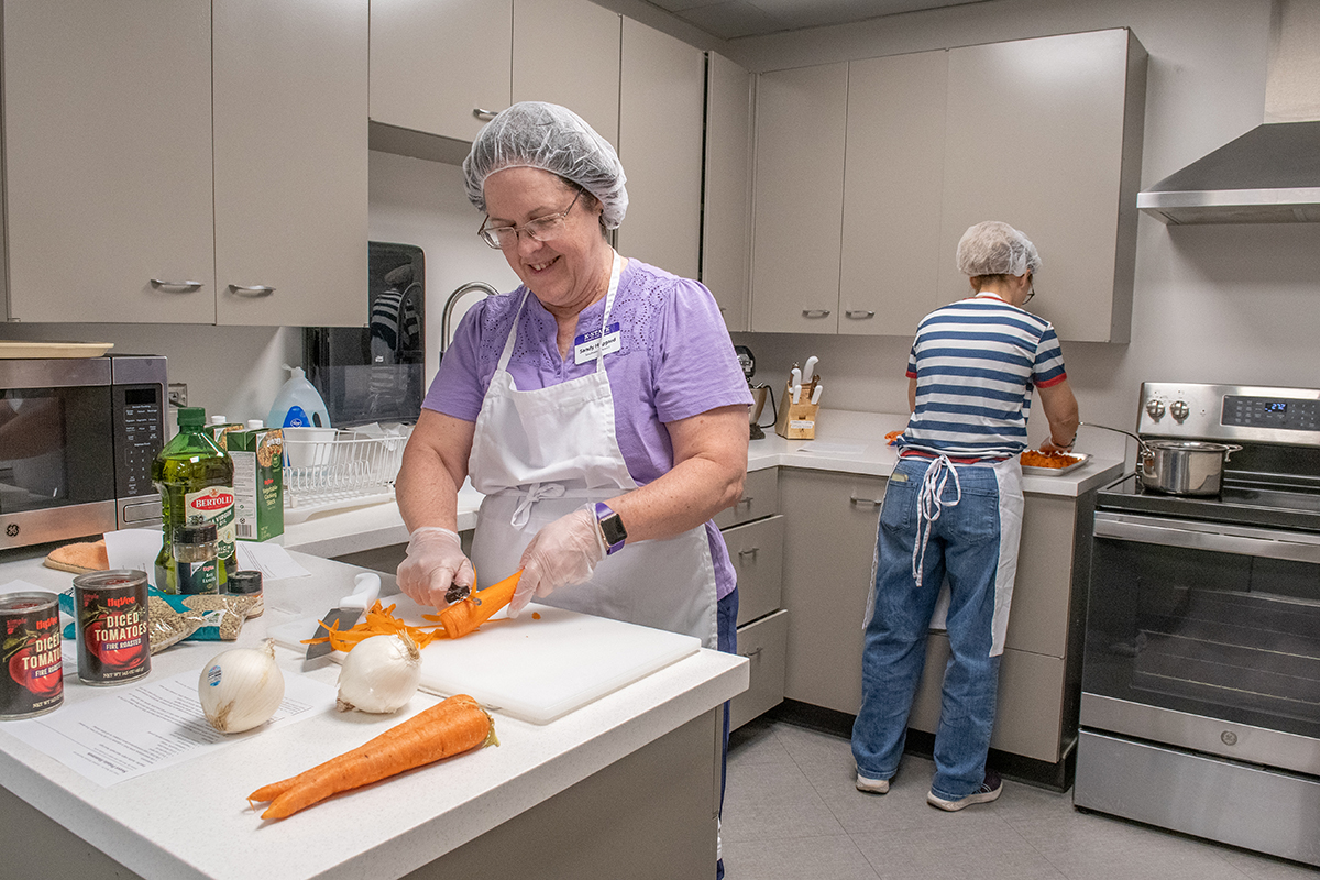 A woman cuts carrots in a kitchen laboratory.
