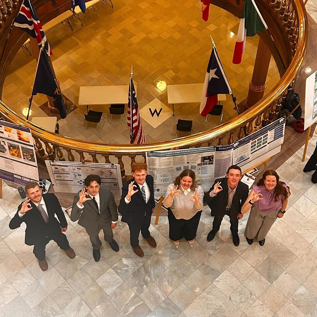 A group of business-dressed undergraduates pose for an above-head photo in a capitol rotunda.