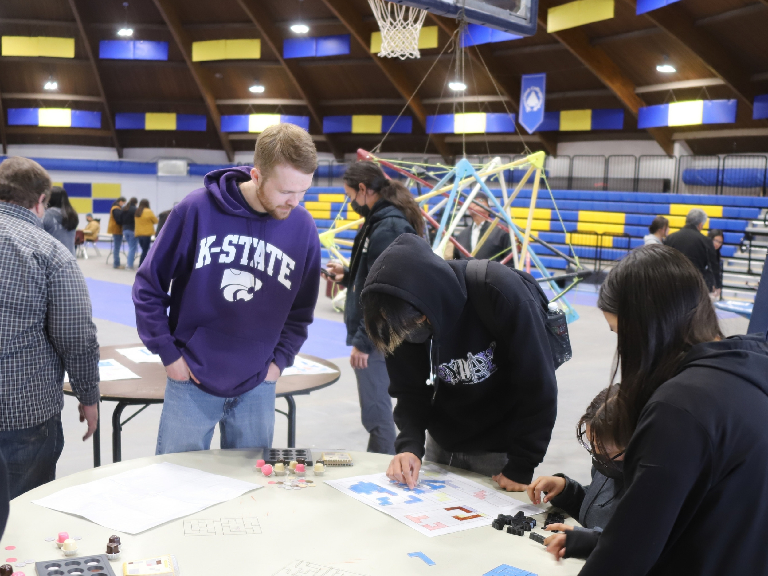 Jesse Osnes looks down at a post on a table with a student during a Diné College outreach program