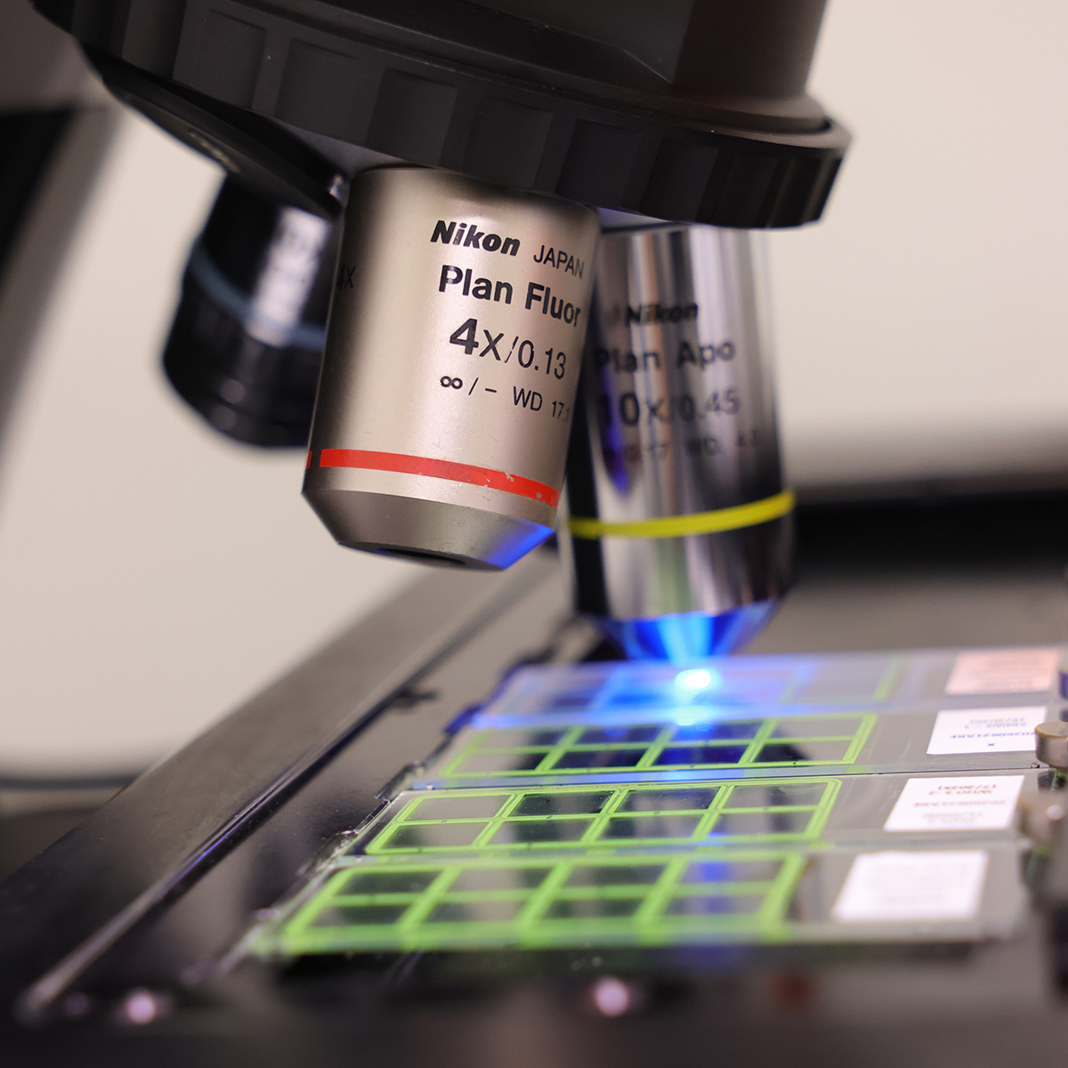 A microscope scans an array on a slide of glass.