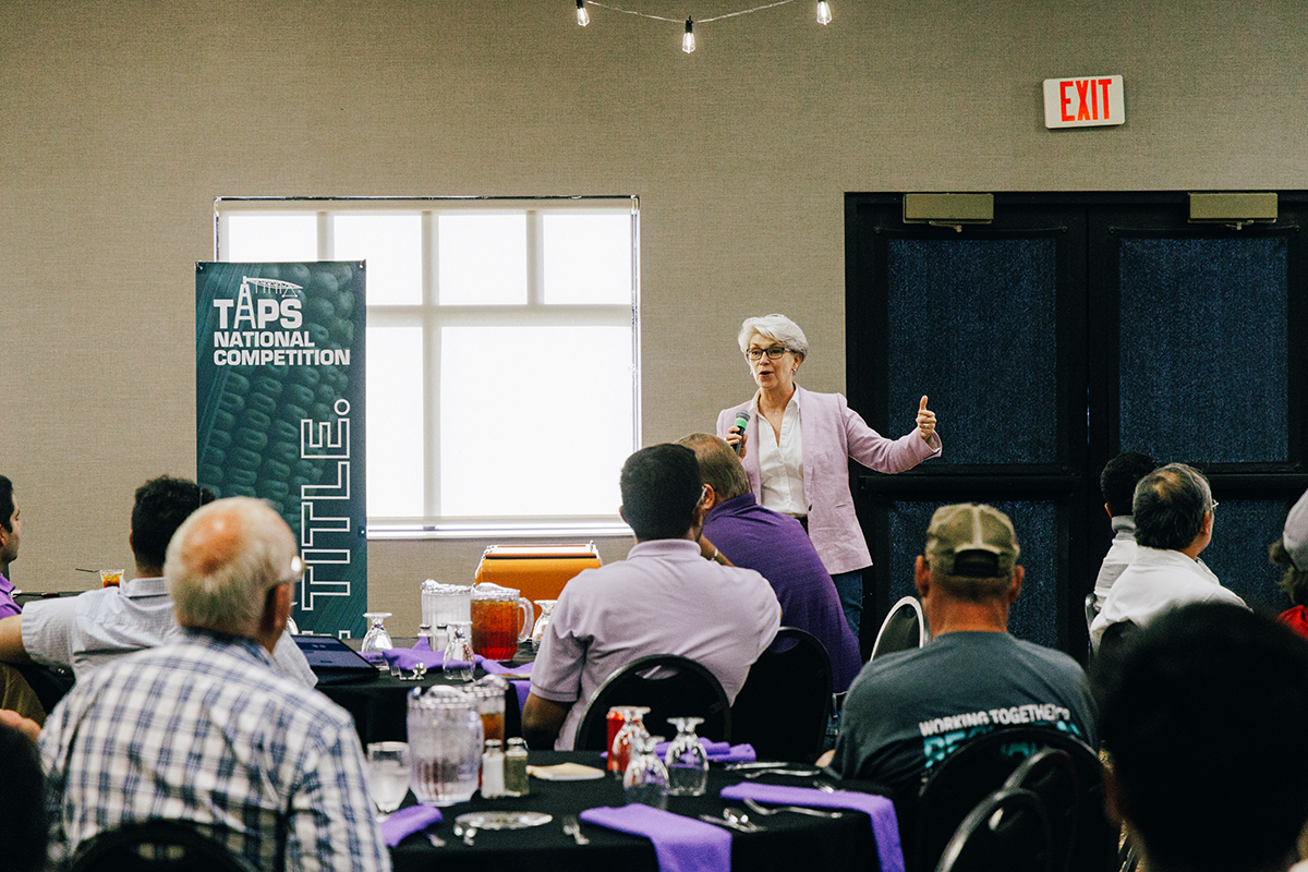 A woman presents to a room of farmers.