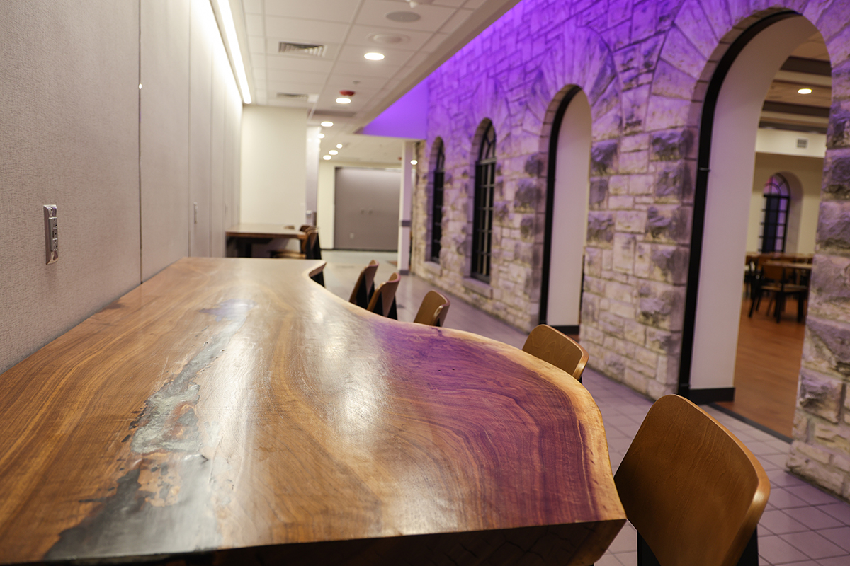 A close-up of a wooden table in a hallway with a pillared limestone feature behind it.