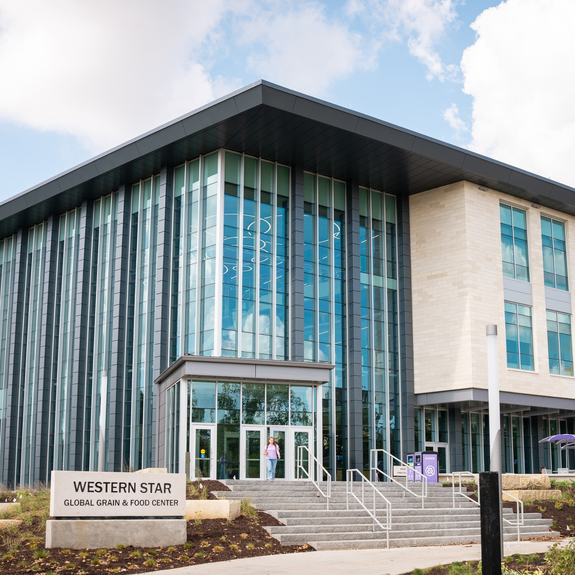 The photo of the exterior of the new Western Star Global Grain and Food Center, featuring tall, glass walls, limestone steps and a limestone sign with the building's name.