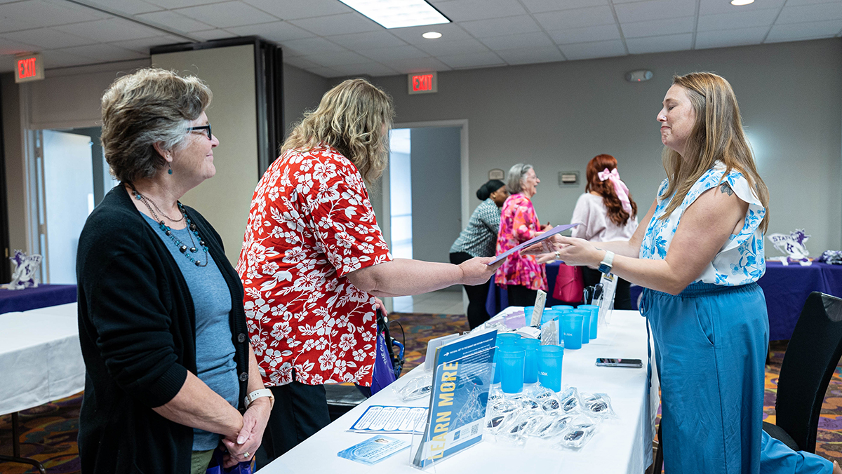 A woman in a blue outfit stands near a booth that has giveaways.