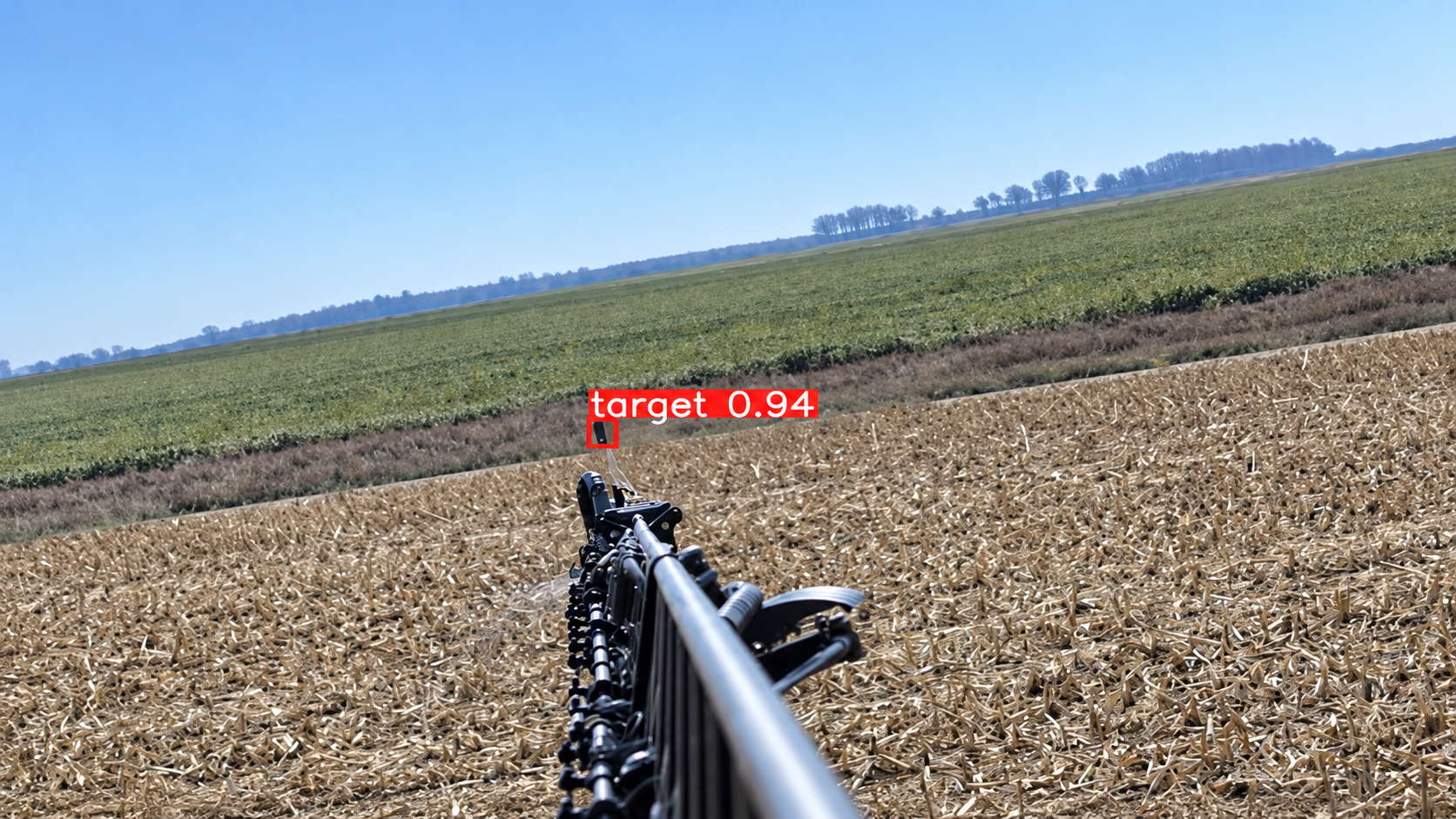 A crop sprayer boom extends out over a harvested field. A red box annotates the end of the boom's arm as being "target: 0.94."