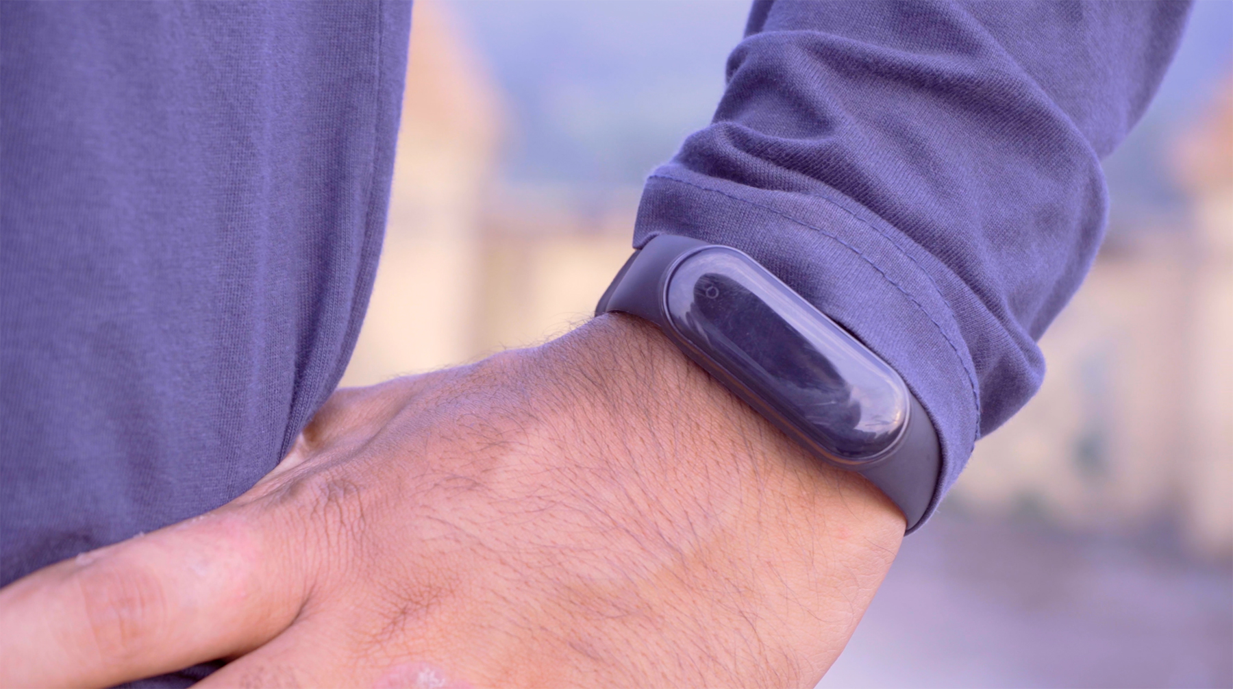 A man in a purple shirt wears a purple Fitbit exercise monitor on his wrist.