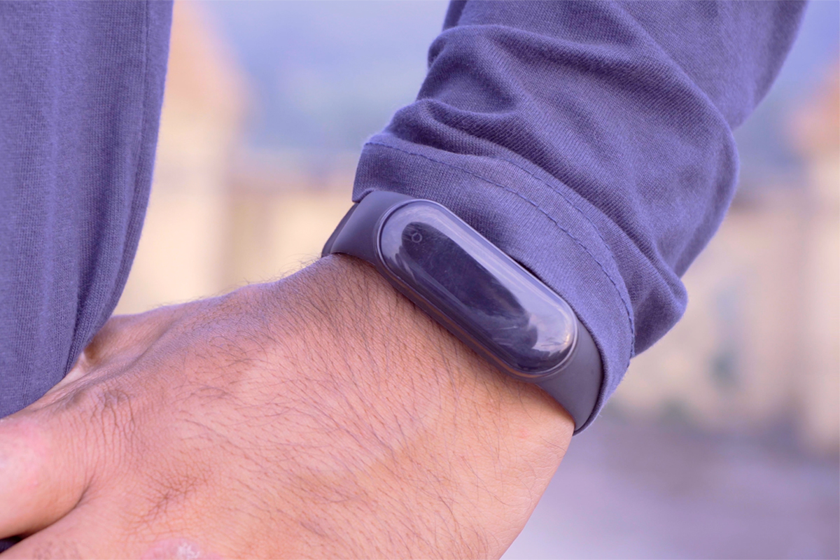 A man in a purple shirt wears a purple Fitbit exercise monitor on his wrist.