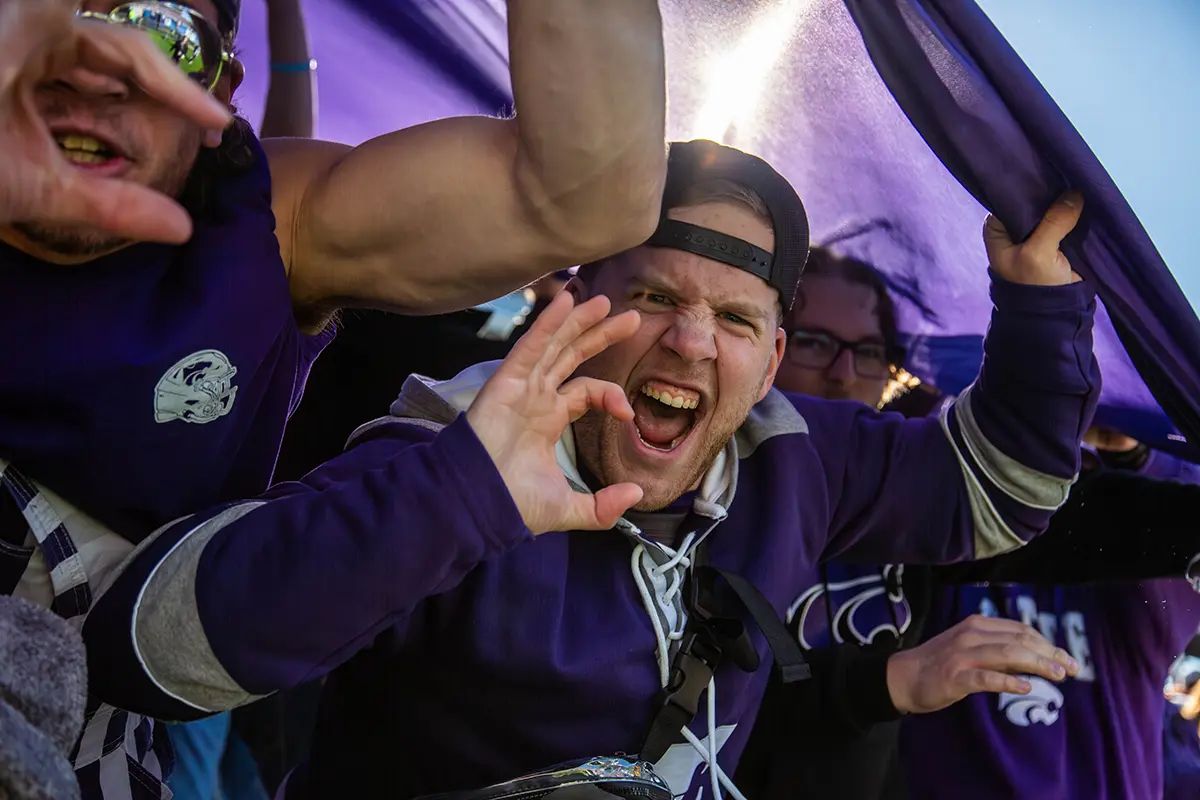 A male student yelling as he holds up the Wildcat hand sign.