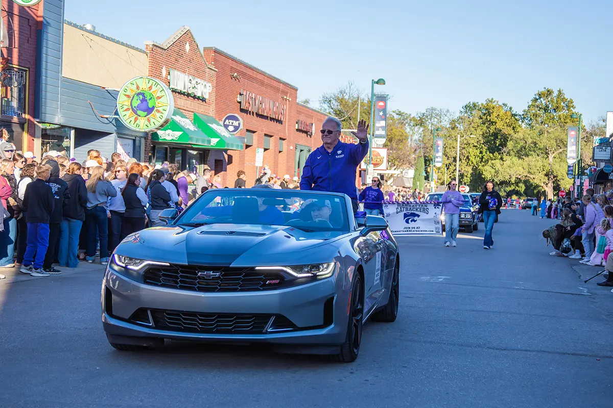 Frank Tracz sitting on the back of a convertable car waving at the crowd.