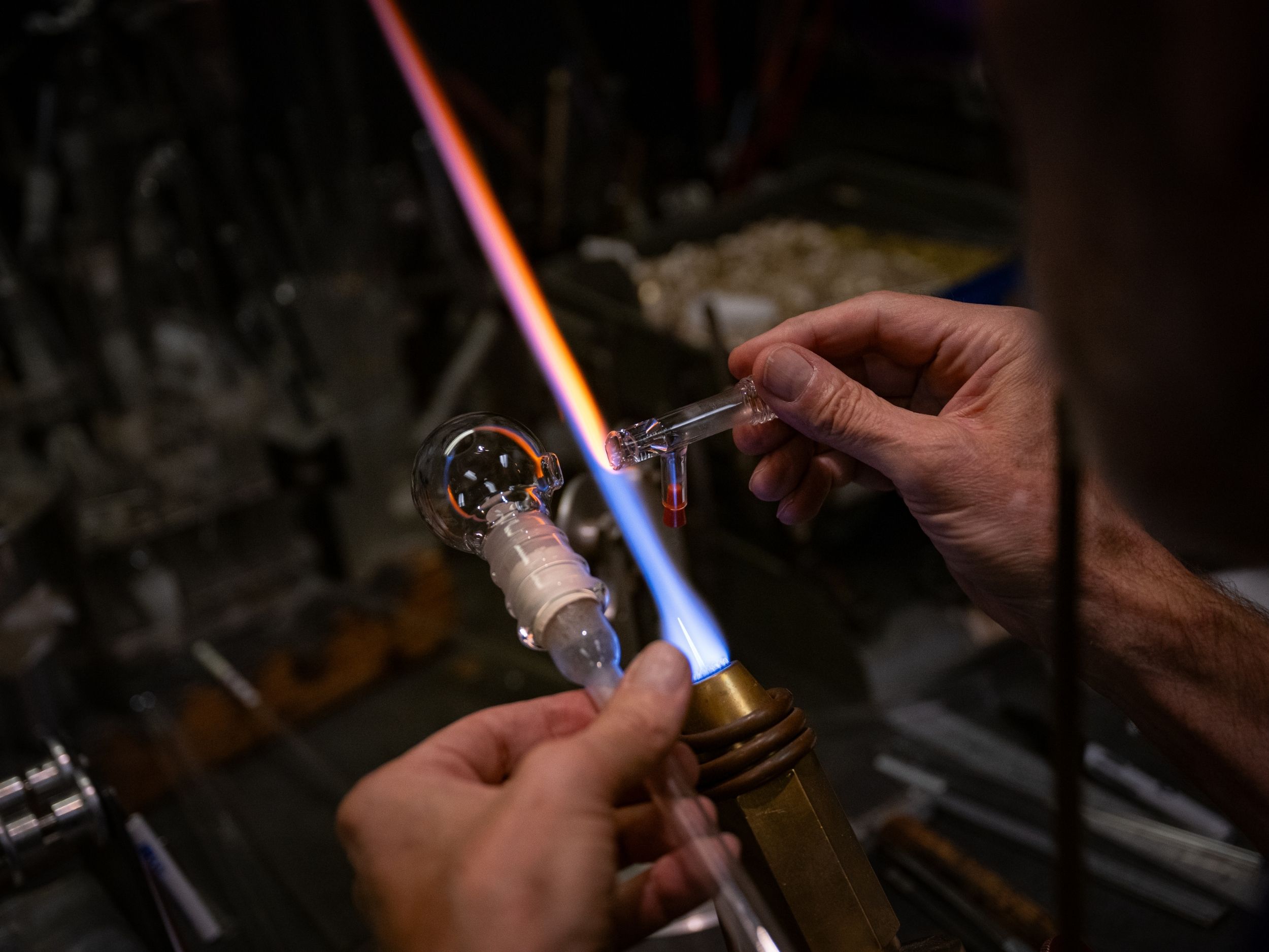 A close-up image of two pieces of glass being fused together by a flame.