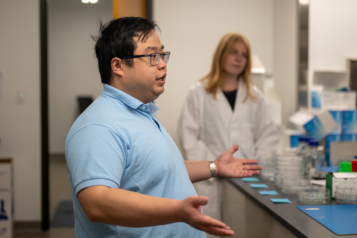 A male college researcher teaaches in a laboratory.