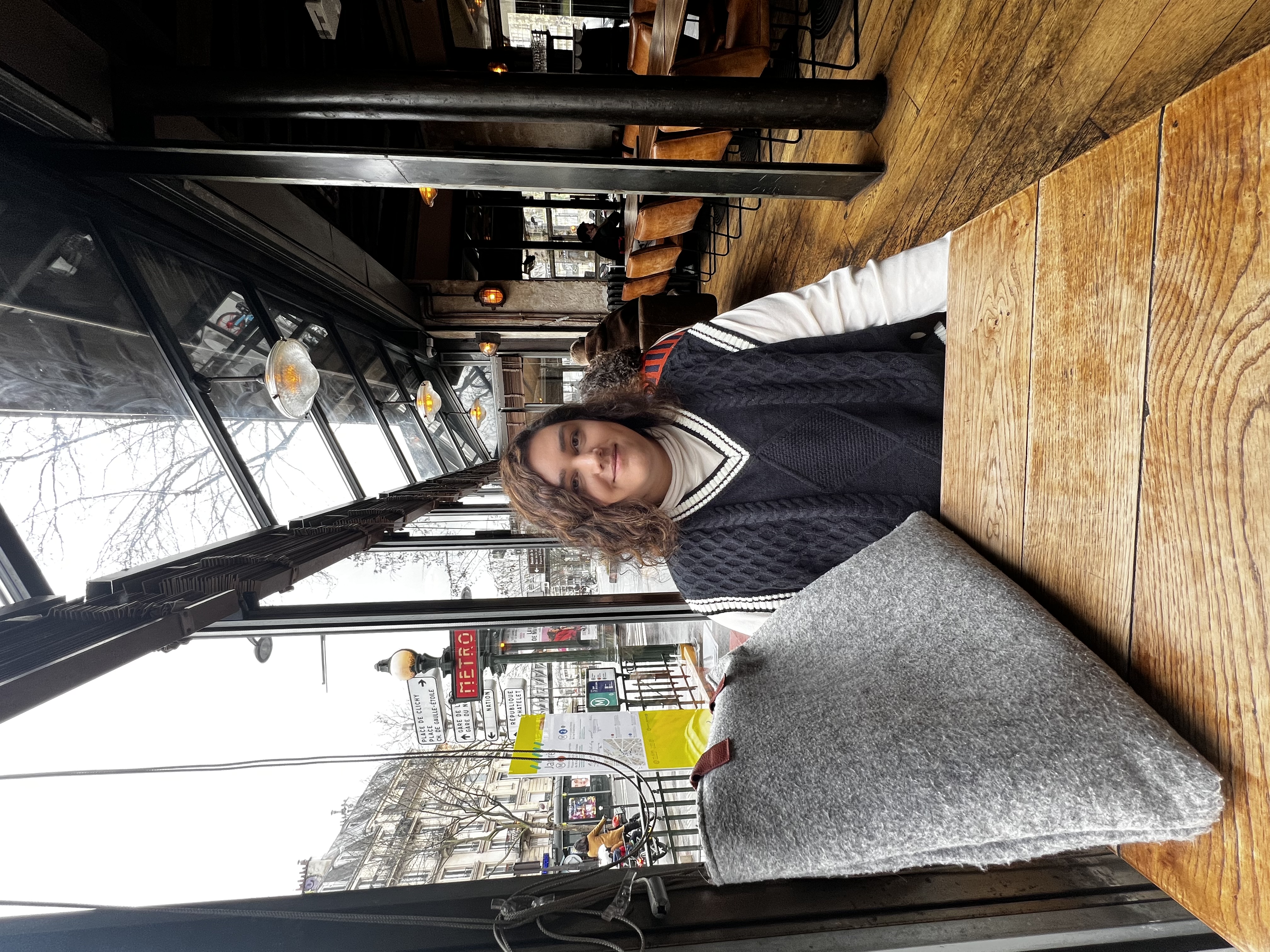 A student in sweater vest pictured sitting at a table in a restaurant.