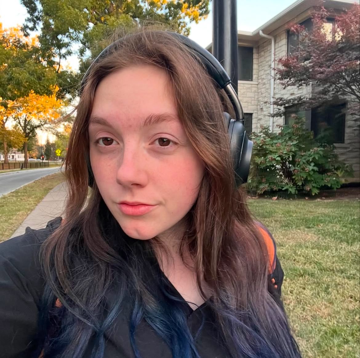 A selfie of a student walking on campus with headphones.