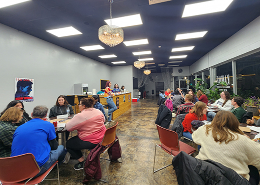 Amelia Bresette, senior in food science, Lee's Summit, Missouri, with Kaitlyn Rhine, senior in public health, Cedar Park, Texas, and Chiara Abou Elias, graduate student in food science, Beirut, Lebanon, behind, facilitates a name-that-song social mixer during the 40th Frontier Field Trip to Council Grove earlier in December.