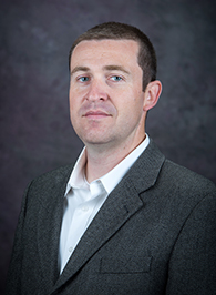 A portrait photo of a white man in a suit
